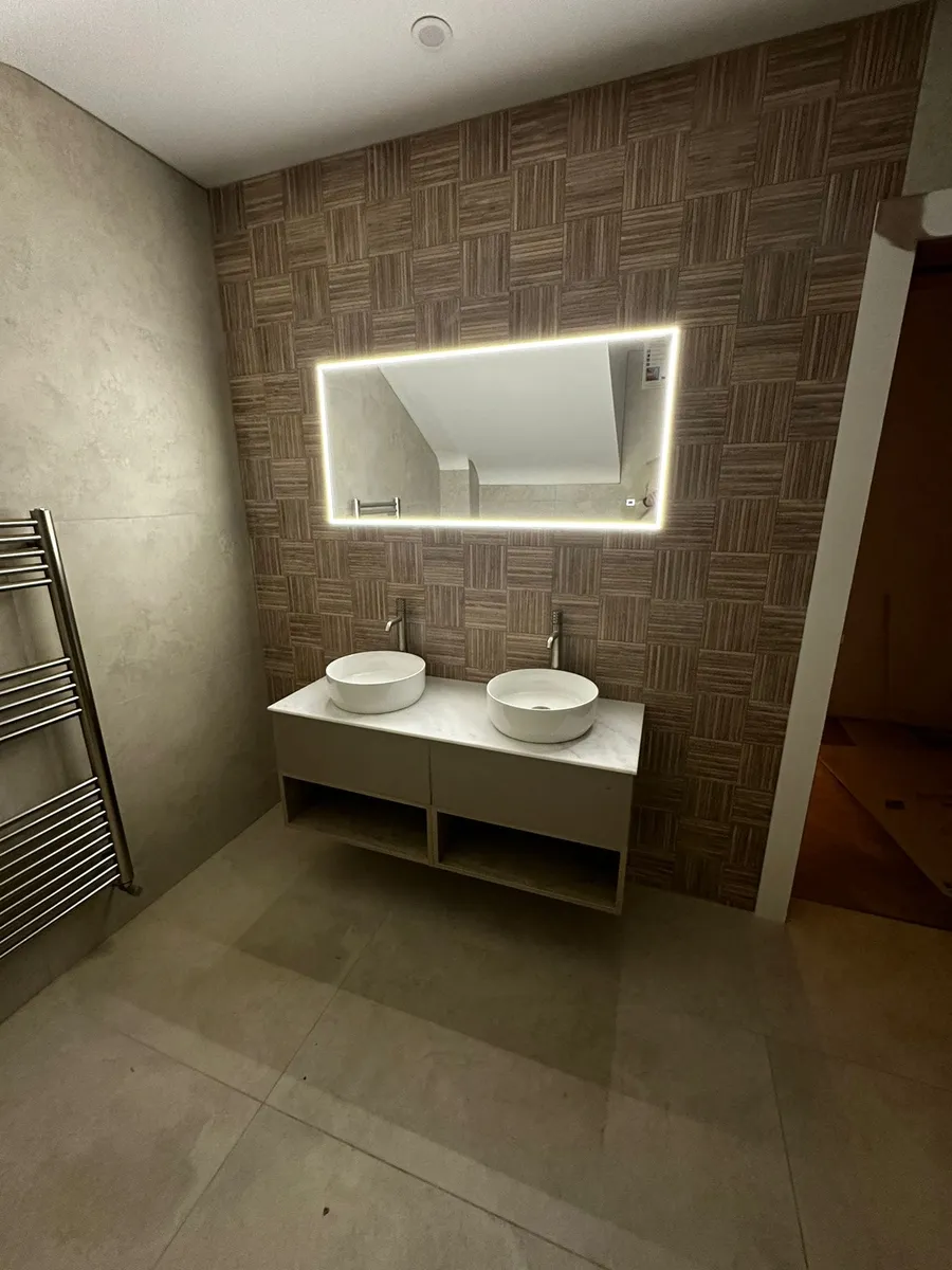 Luxury bathroom with LED backlit mirror, dual vessel sinks and heated towel rail wired by D.O.C Electrical