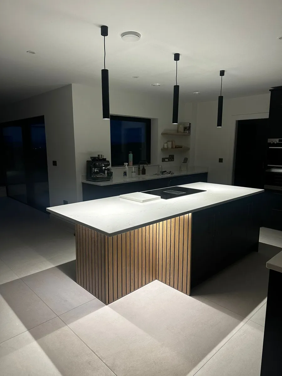 Modern kitchen island with pendant lighting, slatted timber detail and under-counter LED strips installed by D.O.C Electrical